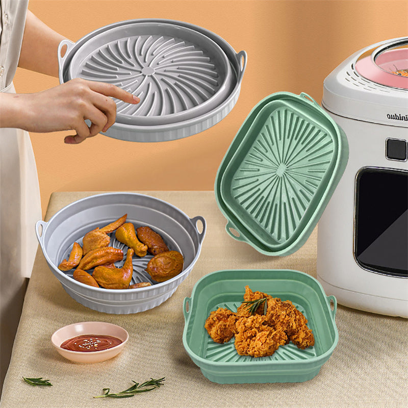 Collapsible silicone food containers with a person pointing at one of them, placed on a table with a kitchen appliance in the background.