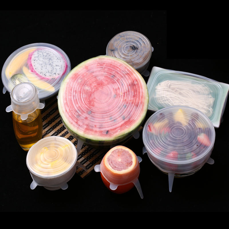 Silicone food covers on various fruits and containers against a black background