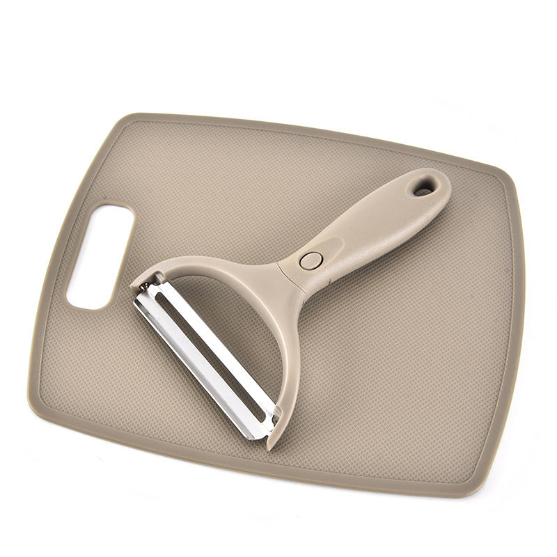 Beige vegetable peeler on a beige cutting board with a white background