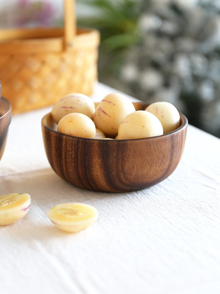 Wooden bowl filled with potatoes on a white surface with a blurred background