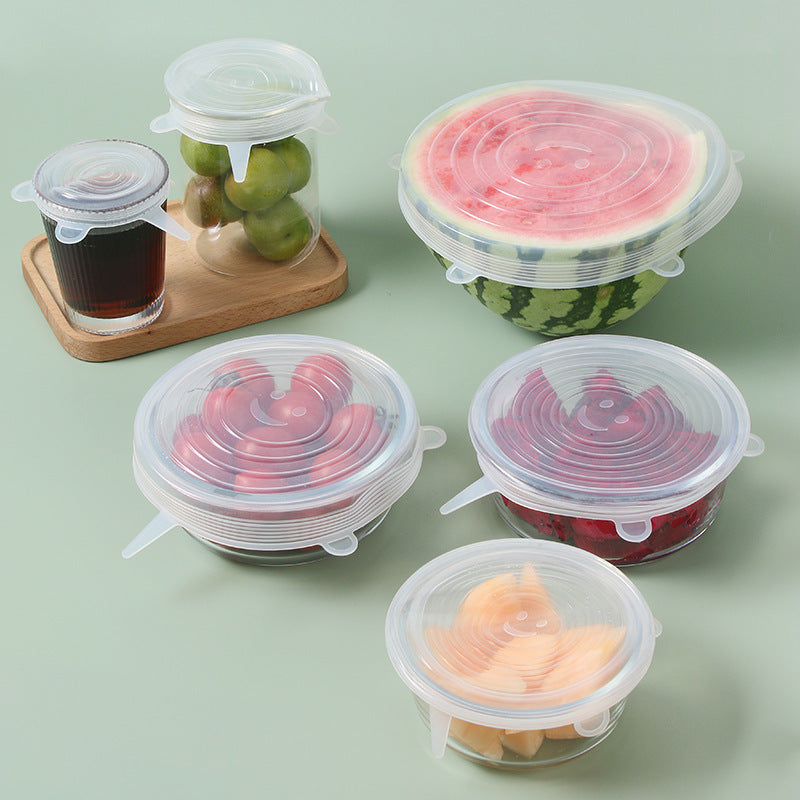Set of silicone food covers on various fruits and containers on a light green background