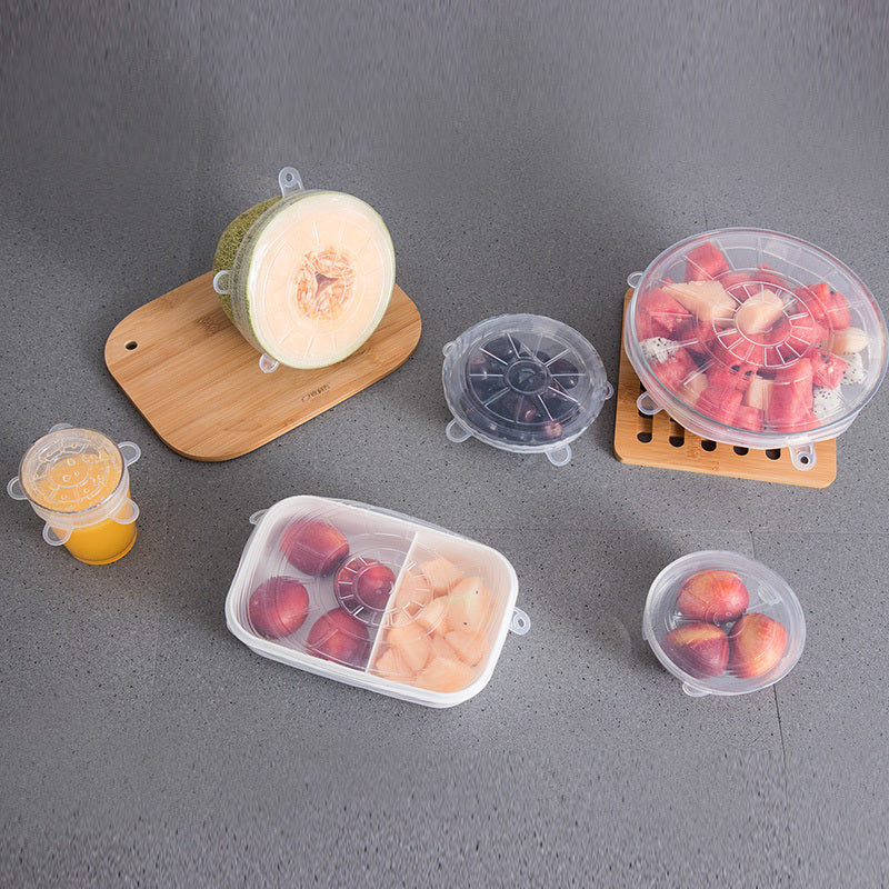  silicone food covers on various fruits and containers on a gray surface